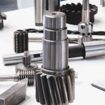 metal mechanical parts on the table. shafts, gears, screws, and milling cutters. tech industrial technology background